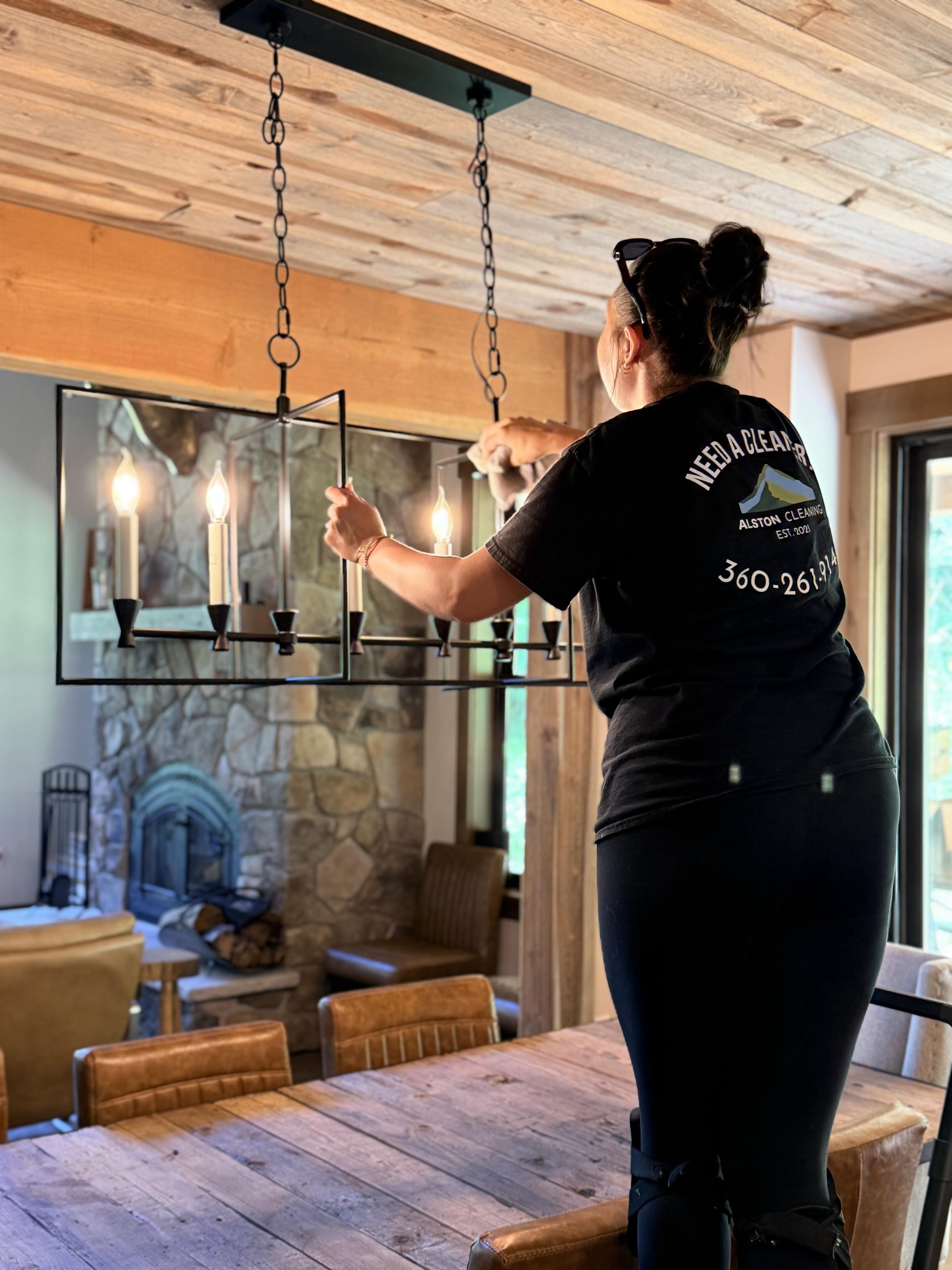 Detail cleaning a chandelier in a residential dining room
